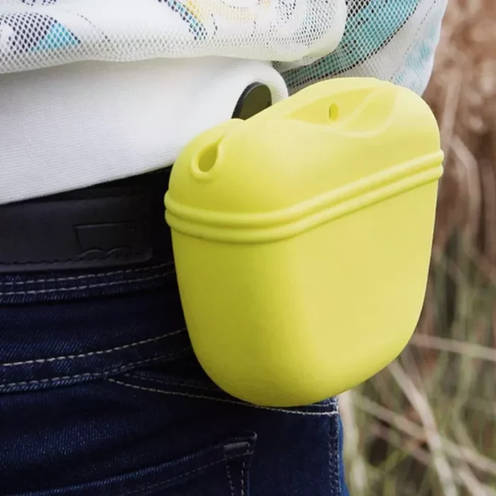 A durable yellow silicone case for wireless earbuds, doubling as a handy treat pouch, is attached to a person's belt loop.