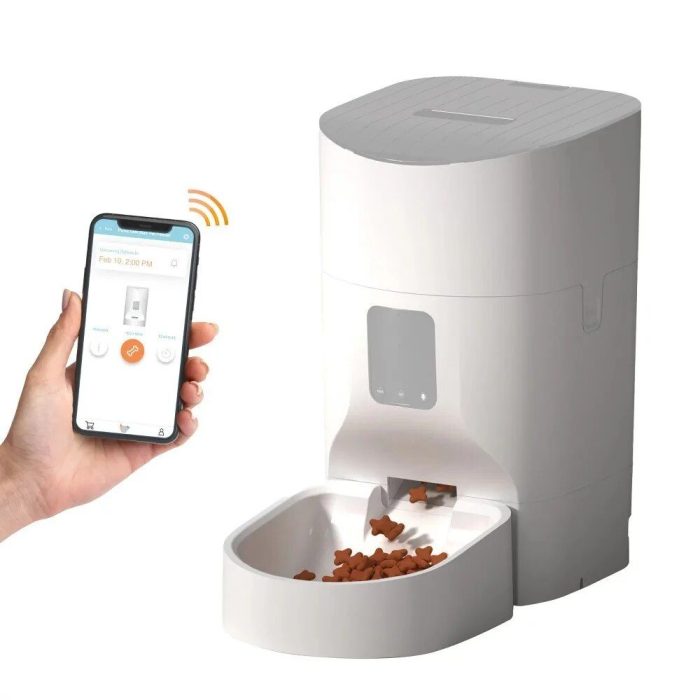 A person holds a smartphone displaying an interactive app control, seamlessly managing a 10266-22be32.jpg dispensing kibbles into a bowl.