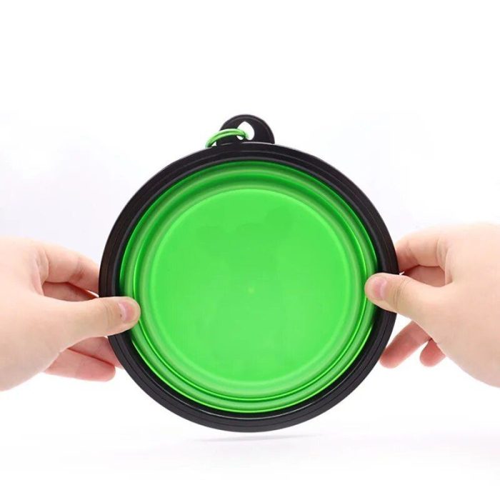 Hands holding a green collapsible 10365-5fef3c.jpg with a black rim against a white background.