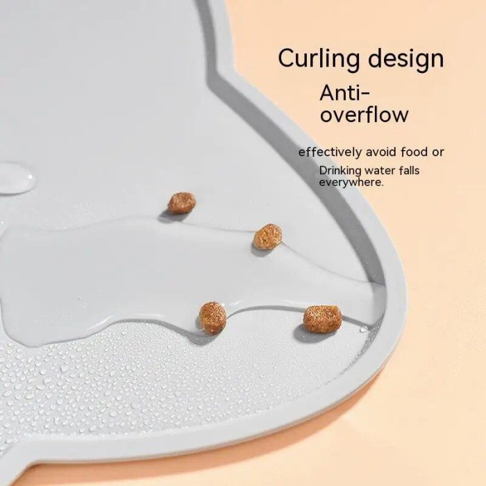 A close-up of 10468-5f701a.jpg with a curled edge designed to prevent water or food spills. Four pieces of pet food and small water droplets are on the mat. Text on the mat reads "Curling design Anti-overflow.