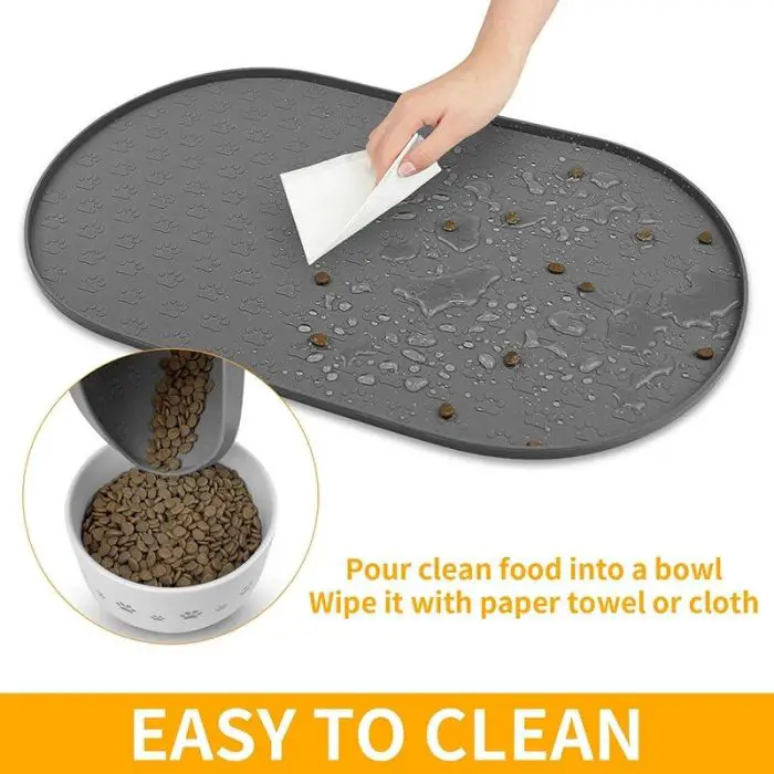 A hand wipes a gray silicone pet feeding mat with a cloth. Water droplets are visible on the mat. An inset image shows dry pet food being poured from the mat into a bowl. Text reads "EASY TO CLEAN." 10573-c6a6bd.jpg makes mealtime mess-free and convenient!