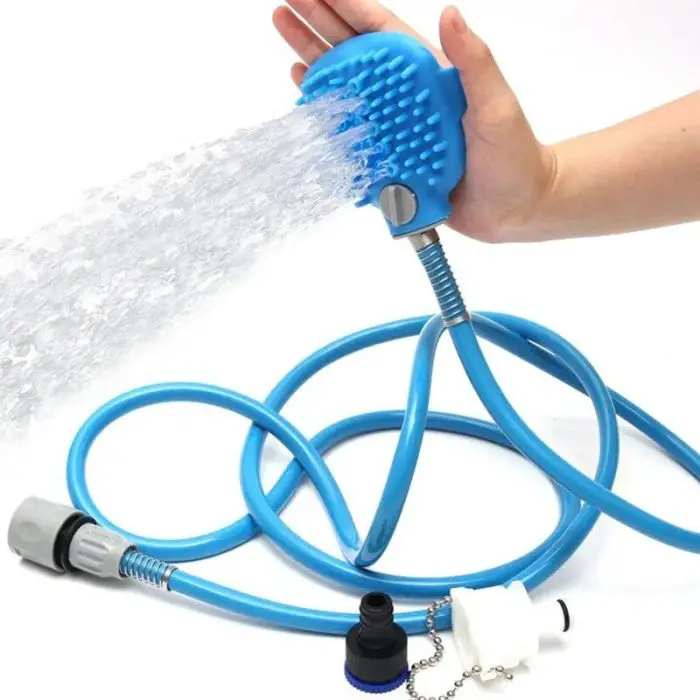 Close-up of 10652-2264f7.jpg with a brush head spraying water, ideal for use as a pet shower. The hose has an attached water control valve and various connectors, being held by a hand.