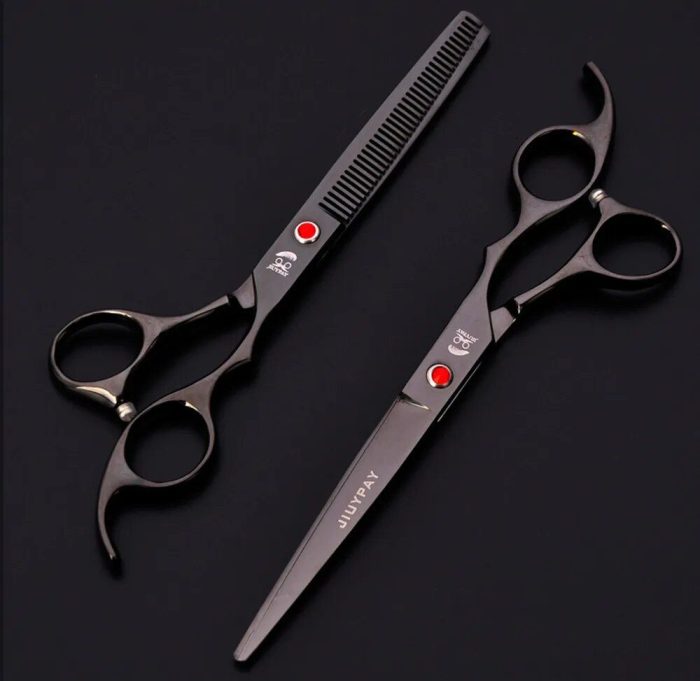 Two black hairdressing scissors, part of a 10684-5ef42c.jpg, rest on a dark surface. One features a comb-like blade while the other boasts straight blades.