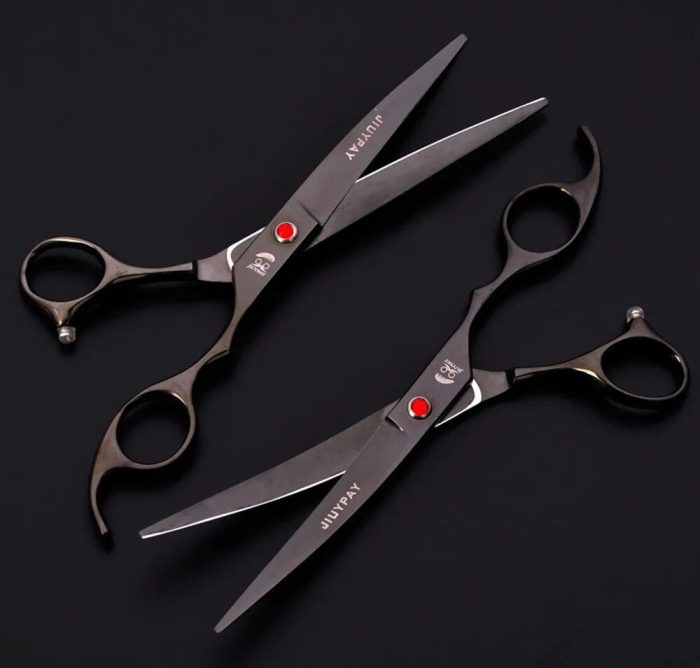 A pair of black hair cutting scissors with curved handles and red accents on a black background, perfect for any 10684-f5b6bf.jpg.