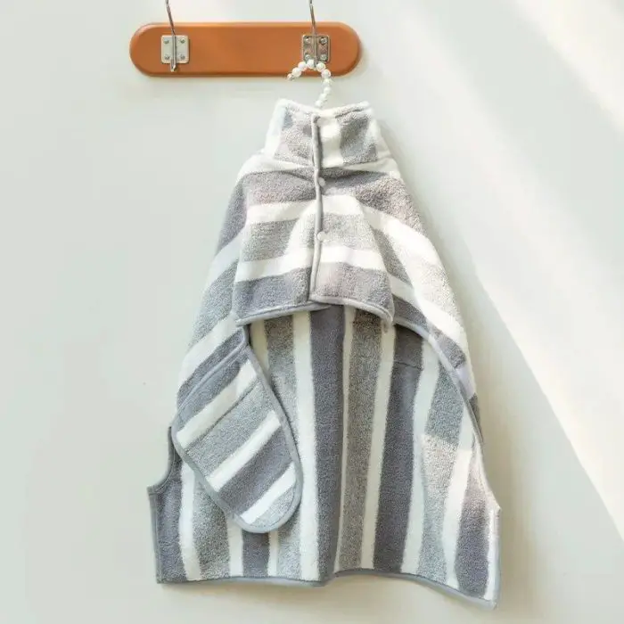 A gray and white striped fleece bathrobe hangs from a small wooden rack on a white wall, 10726-067837.jpg.