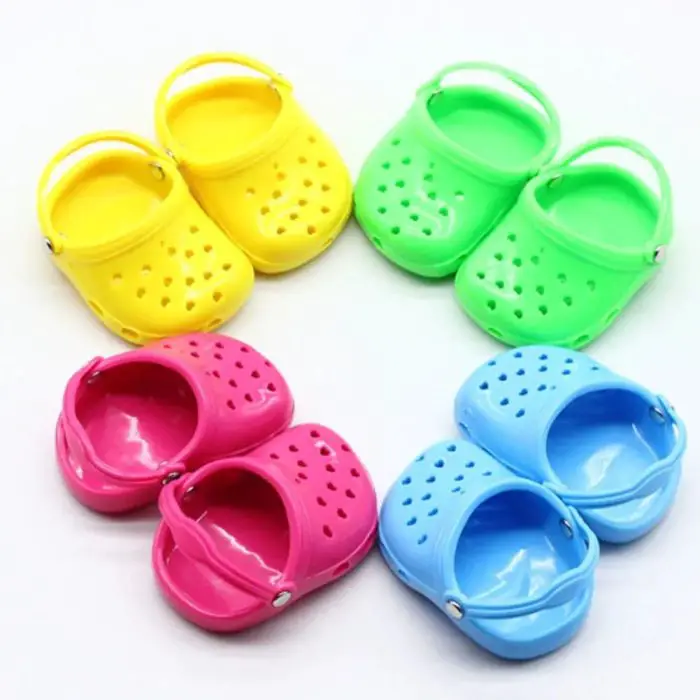 Four pairs of small, brightly colored plastic dog sandals (10769-9cef04.jpg) are arranged in a circle on a white background. The shoes are yellow, green, pink, and blue.