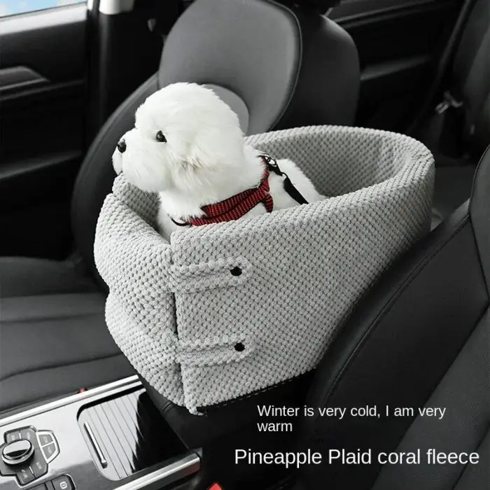 A small white dog sits in a gray, textured 10958-093a32.jpg on a car seat. The carrier is secured with straps. Text reads: "Winter is very cold, I am very warm. Pineapple Plaid coral fleece.