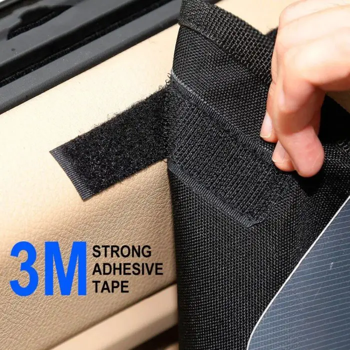 Close-up of a hand attaching a black fabric strip using strong adhesive tape to a beige surface. Text on the image reads "11032-ae0391.jpg." This method ensures your waterproof dog car door cover protector stays securely in place, no matter the conditions.