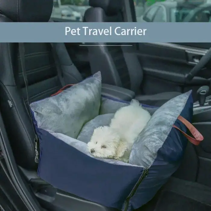 A small white dog rests inside a gray and blue pet travel carrier placed on a 11076-7ea0b5.jpg. The seat is part of a leather car interior.