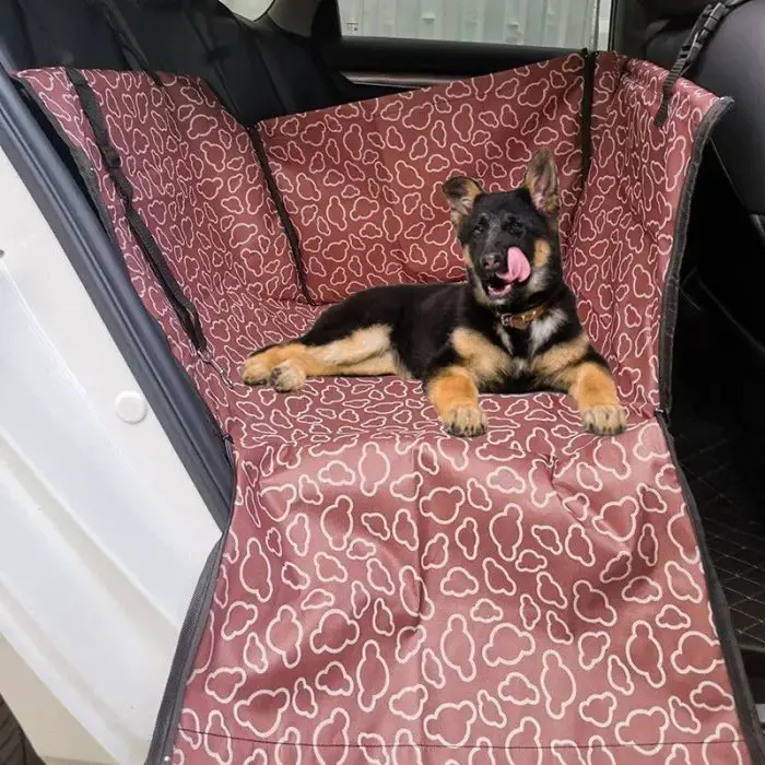 A German Shepherd puppy lies on a 11084-757e29.jpg in a car, licking its nose.