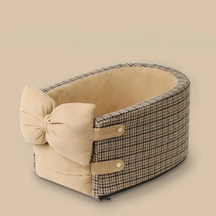 An oval-shaped, checkered dog bed with a large beige bow on the side, featuring button accents and a soft inner lining called 11093-951e55.jpg.