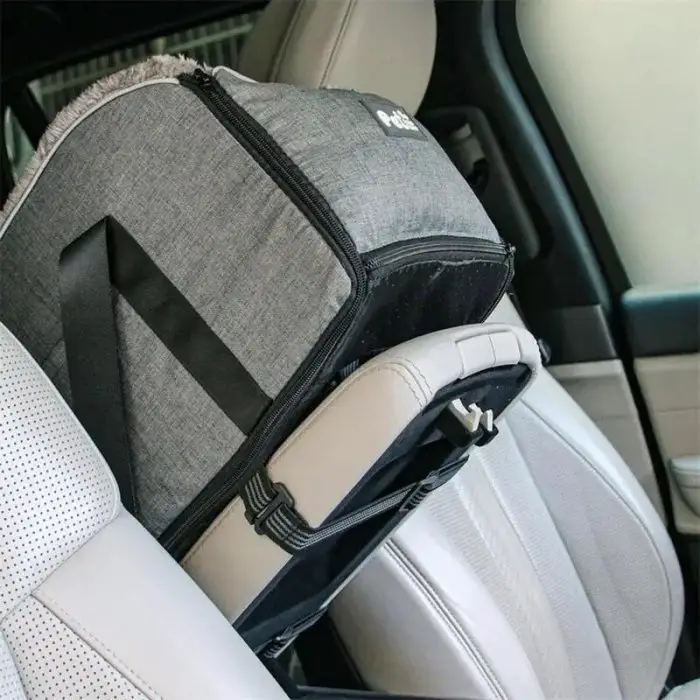 A gray 11110-2270a6.jpg, acting as a booster seat, securely fastened to the passenger seat of a car with black straps.