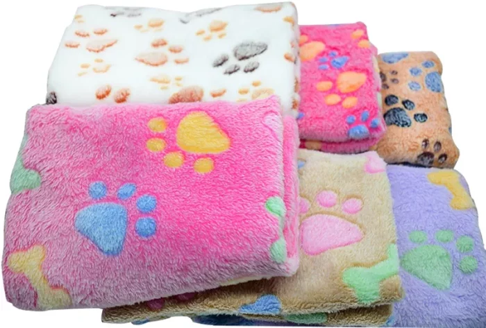 A collection of folded, colorful fleece blankets with paw print patterns in various hues including pink, white, beige, and purple (Product Name: 11395-caf500.webp).