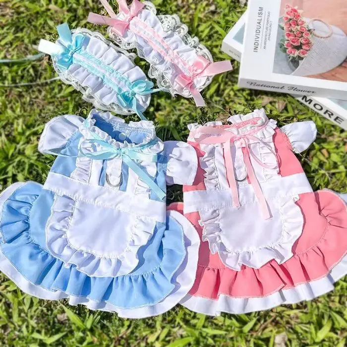 Two adorable pet dresses, one in a charming blue and the other in a lovely pink, each with matching headbands labeled as product 11844-96a1e7.jpg, were laid out on the grass—ideal for an irresistibly cute costume.