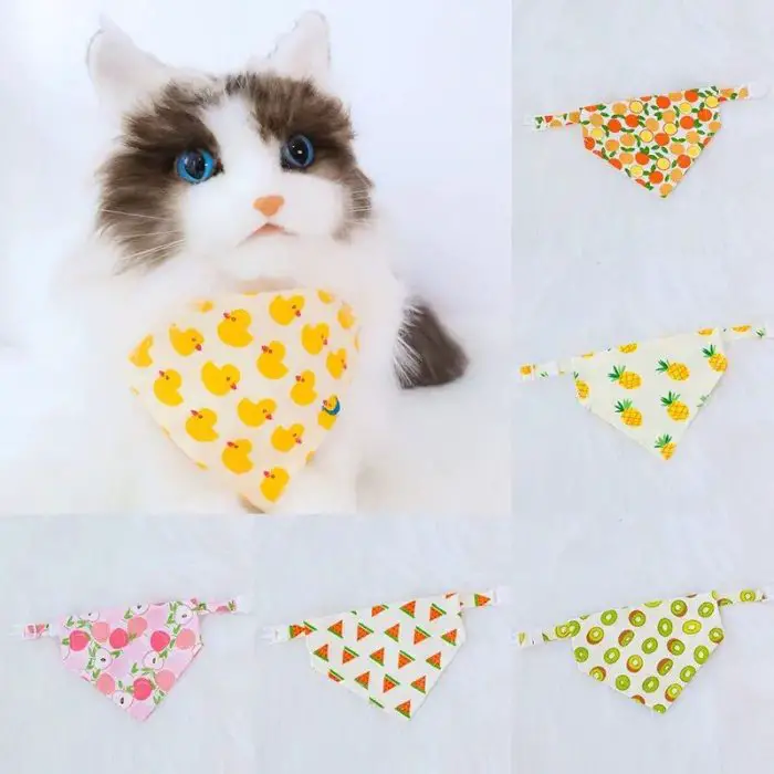 A plush cat wearing a yellow bandana with a charming duck pattern, accompanied by five other colorful bandanas adorned with various fruit and triangle designs. Product image file: 11880-0f75bc.jpg.