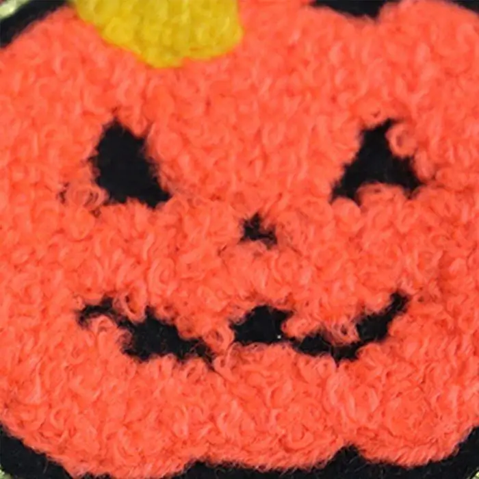 Close-up of the product "11881-823eec.jpg," highlighting its crocheted pumpkin face adorned with black eyes and a mouth, a yellow stem on top, and a tiny bandana around its neck.