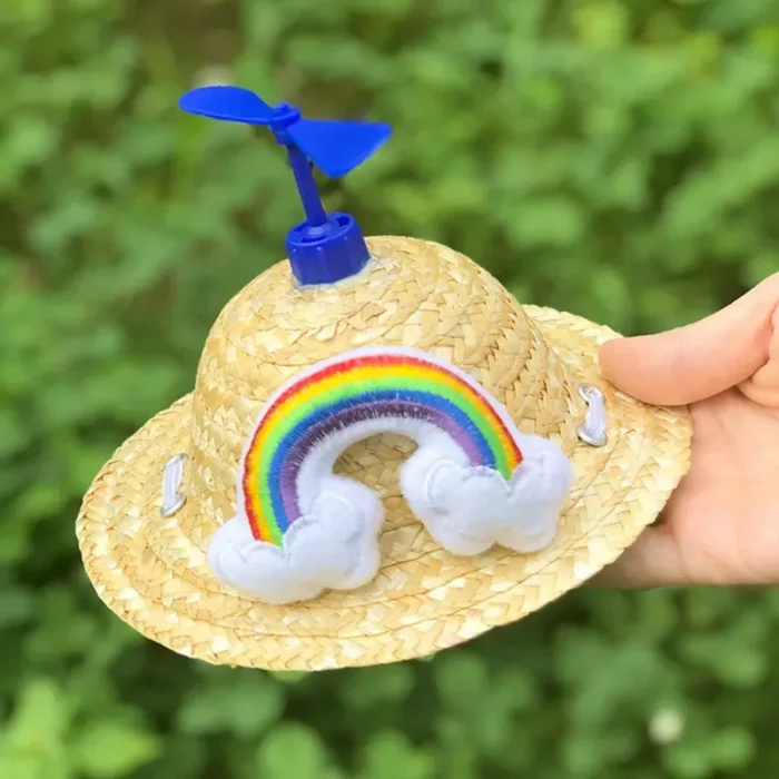 A small sun hat, featuring a blue propeller on top and adorned with a rainbow and clouds design on the front, is depicted in product image 12313-b566ed.webp.