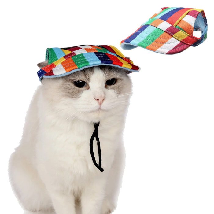 A white cat dons the 12318-6fc9df.jpg pet cap, which features a multicolored checkered pattern and a strap under its chin. A matching cap of the same style floats above the cat to the right.