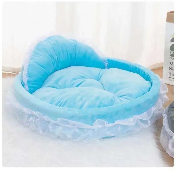 A blue heart-shaped dog bed with white frills from the product 12440-263fd4.jpg is placed on a light-colored surface.