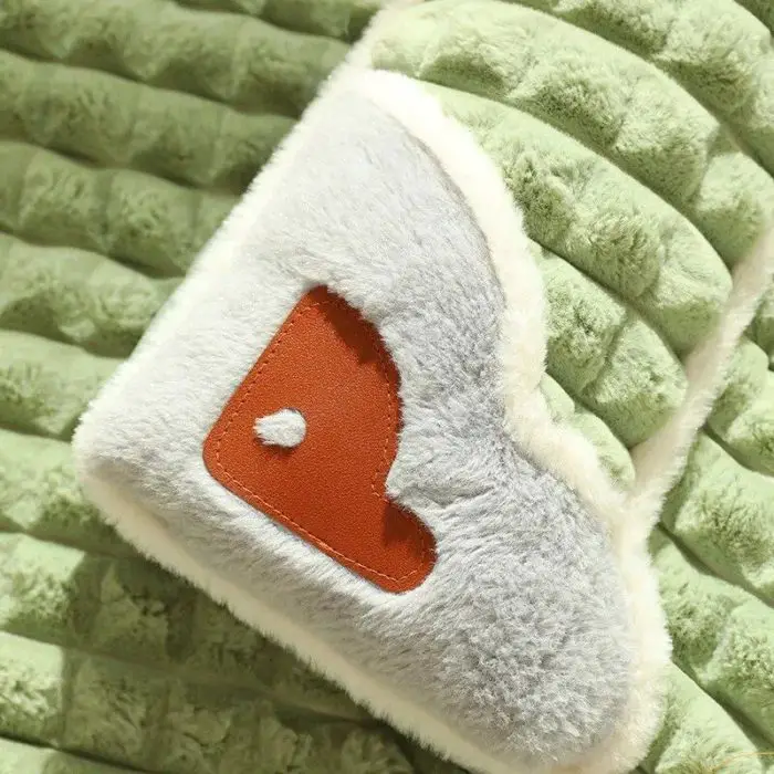 Close-up of a green quilted fabric on a cozy pet bed, featuring a fuzzy white heart-shaped patch with a small orange heart design. (Product Name: 12444-469286.jpg)