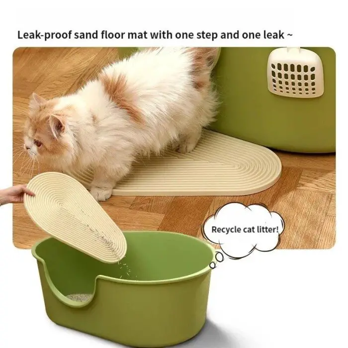 A fluffy white and orange cat steps onto the 12593-1ef47f.jpg, a leak-proof sand floor mat, placed next to a green cat litter box. An illustration depicts how the mat can be lifted to recycle cat litter.