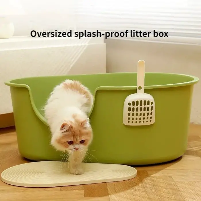 A small, fluffy white and orange kitten steps out of a large green cat litter box with a scooper hanging on the side. Text above the box reads "12593-7d8c9d.jpg.