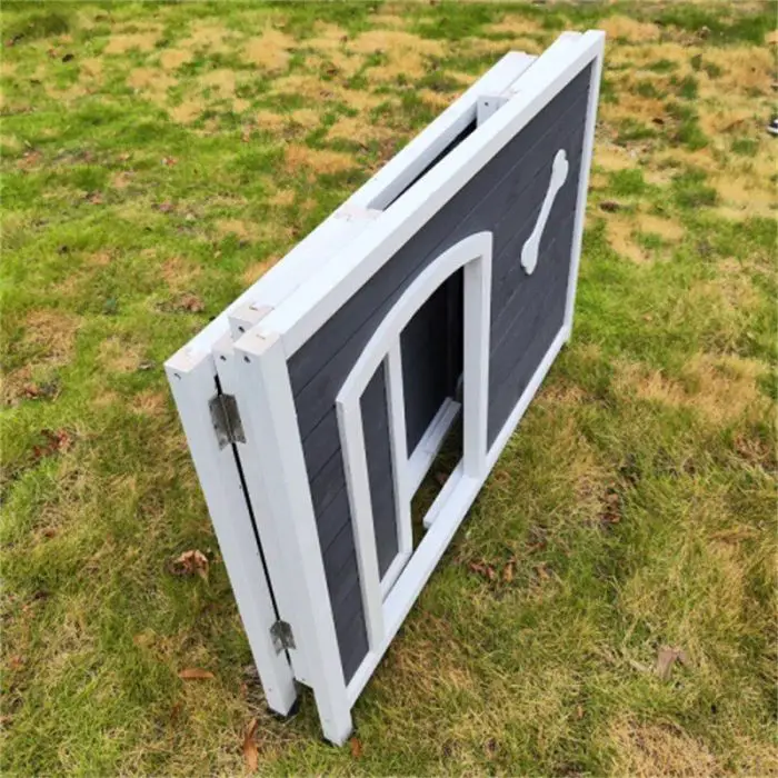 A folded black and white wooden pet door with a bone design, known as 12744-b8c5ed.jpg, lies on the grassy surface, ready to be installed in your dog's house.