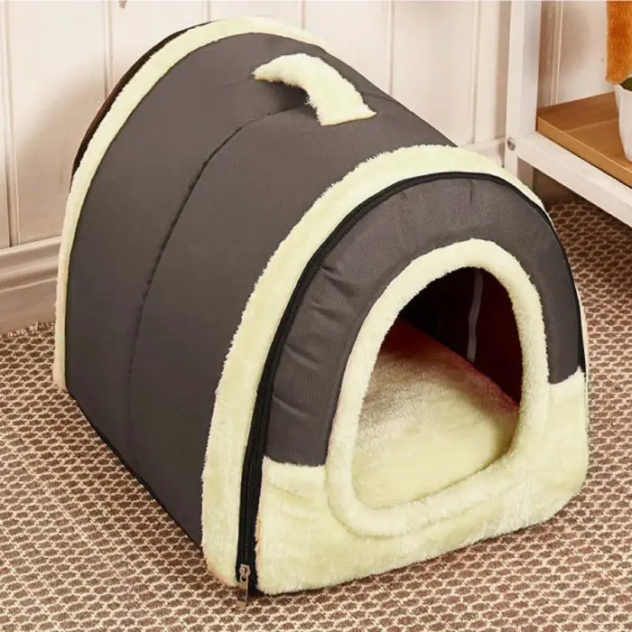 A small, igloo-shaped dog house, identified as 12748-aabc3d.jpg, featuring a gray exterior and cream-colored interior trim, set on a patterned carpet in a room with white paneled walls.