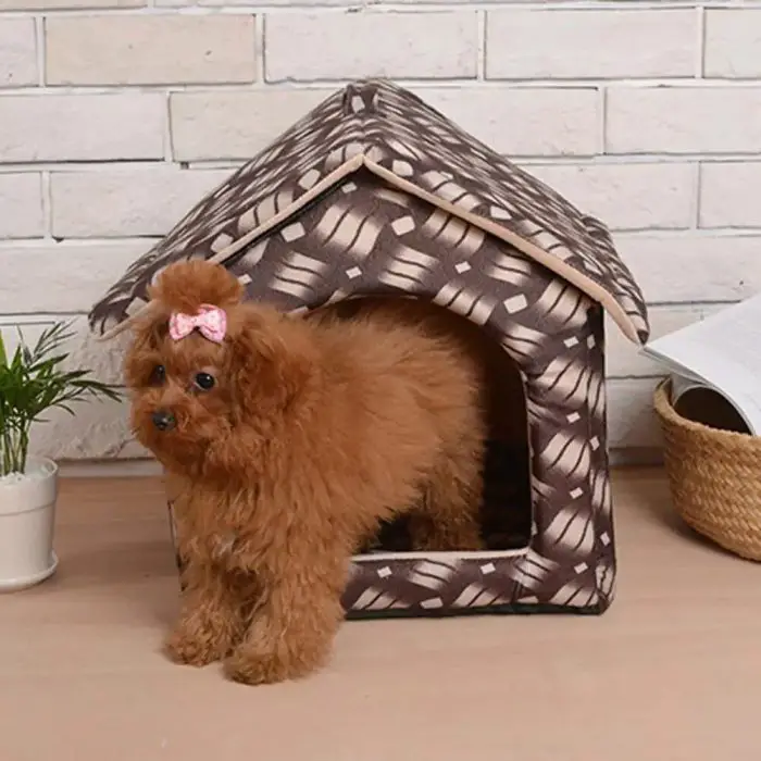 A small brown dog with a pink bow stands at the entrance of the fabric foldable dog house shown in product image 12785-5fa2ad.jpg. A potted plant is situated on the left, while an open book rests in a wicker basket on the right.