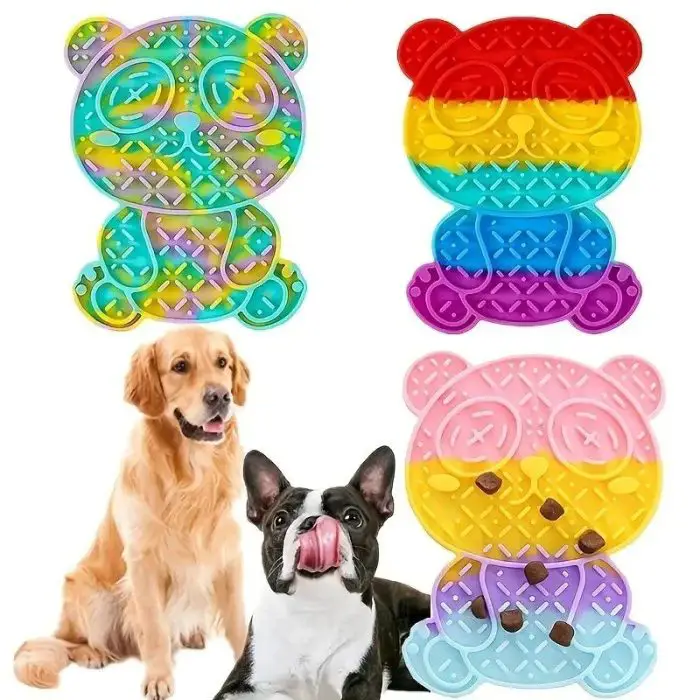 Four bear-shaped colorful silicone mats next to a golden retriever and a French bulldog licking their lips. These Bear-Shaped Silicone Slow Feeder Mats, depicted in product image 12990-b9ad55.jpg, have a textured surface designed to spread treats for pets, making mealtime fun and effective.