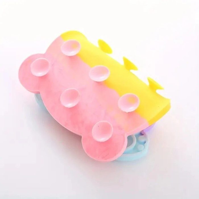 The 12990-c5cb67.jpg is a bear-shaped slow feeder silicone scrubber featuring a pink and yellow gradient design and multiple suction cups on one side.