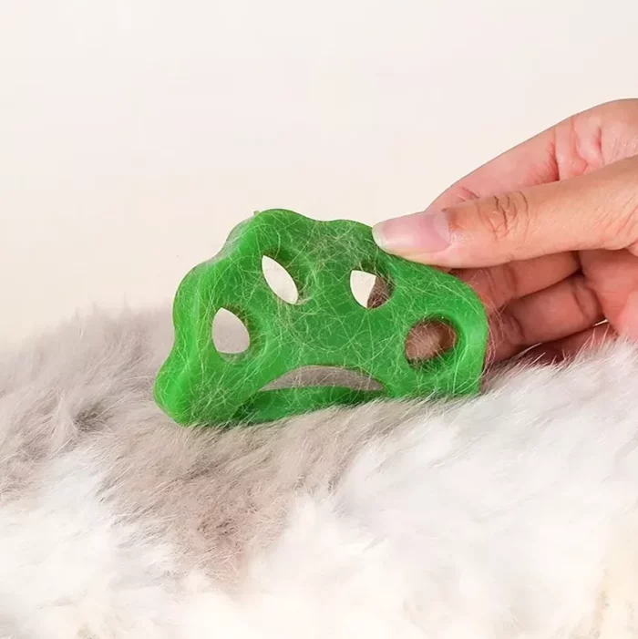 A green, eco-friendly pet grooming tool is being used on a furry surface, with a hand holding the reusable silicone 9573-ea08a3.webp.