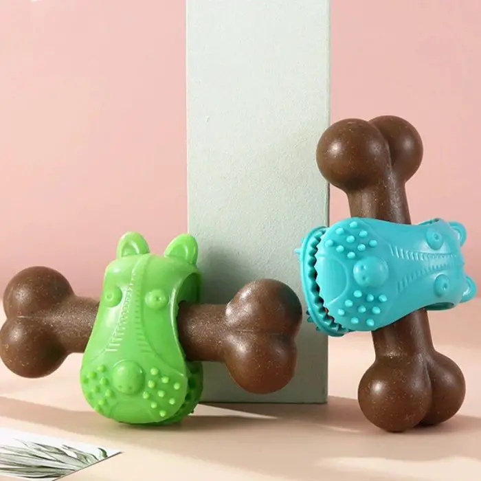 Two brown bone-shaped rubber pet chew toys. One has a green rubber holder, and the other a blue rubber holder, both with textured surfaces, leaning against a light green post (9804-a41f94.jpg).