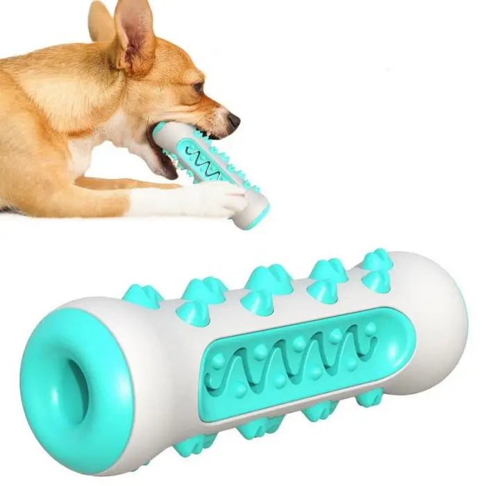 A tan dog is chewing on a white and teal spiked cylindrical 9986-339698.png. The image highlights the toy's texture and design aimed at engaging and entertaining puppies and dogs while promoting dental health.